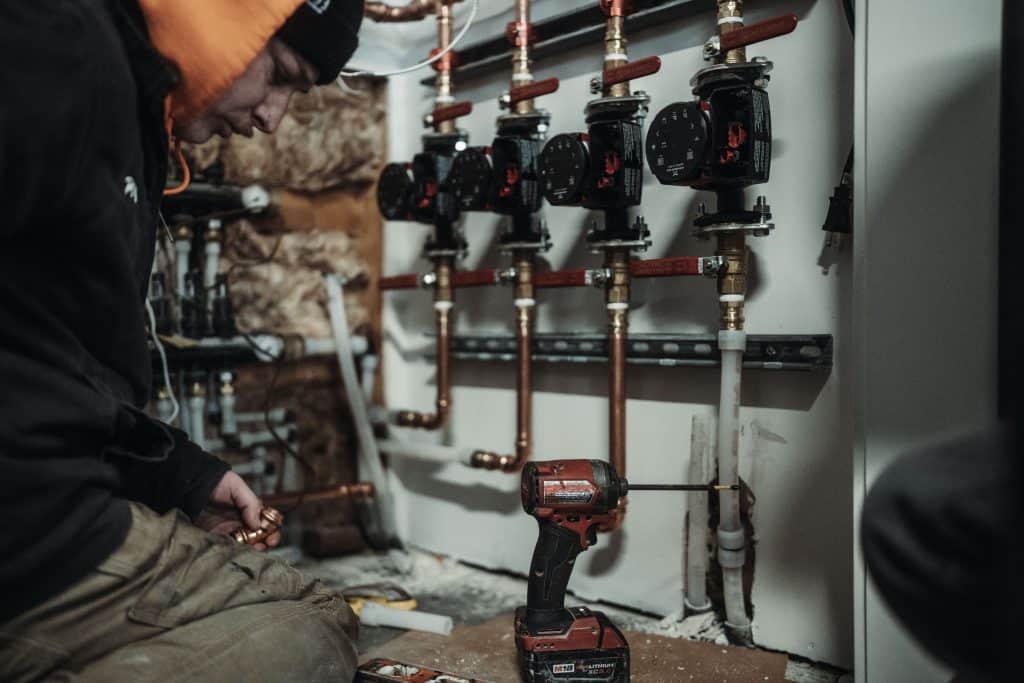 Plumbing professional working on an indoor pipe and valve system
